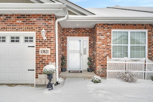 snow covered property entrance with a garage