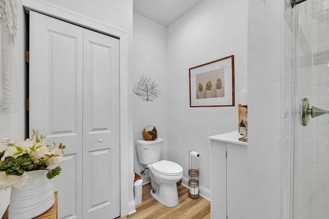 bathroom featuring walk in shower, hardwood / wood-style floors, and toilet