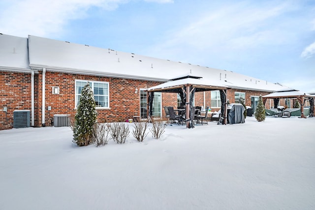 snow covered rear of property featuring a gazebo and central AC