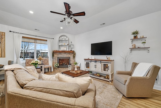 living room with light hardwood / wood-style floors, ceiling fan, and a fireplace