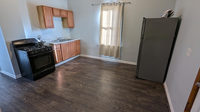 kitchen with gas stove, dark hardwood / wood-style flooring, stainless steel refrigerator, and sink