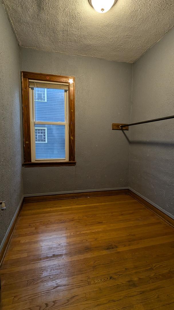 unfurnished room with hardwood / wood-style flooring and a textured ceiling