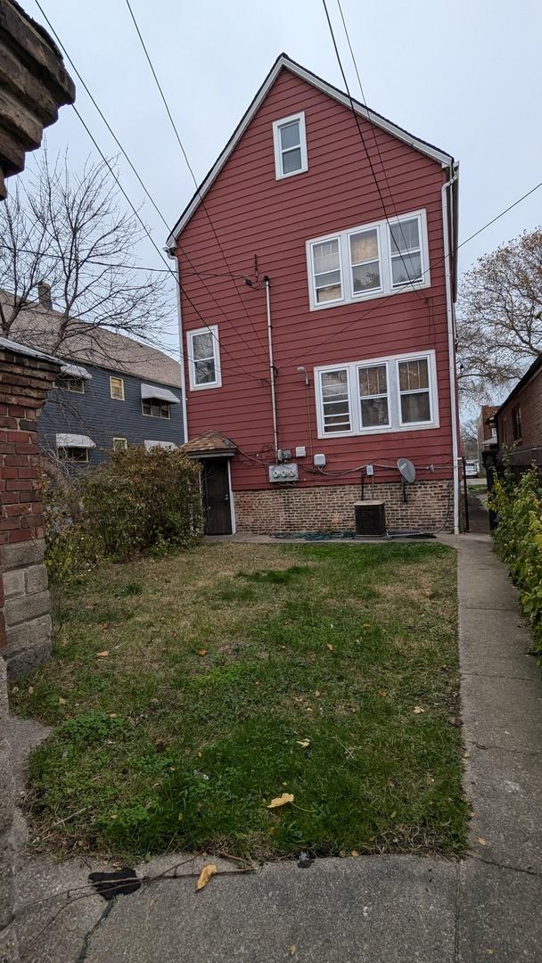 rear view of house featuring central AC unit and a yard