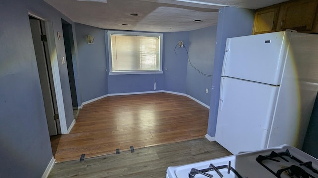 kitchen with white appliances, a textured ceiling, and light hardwood / wood-style floors