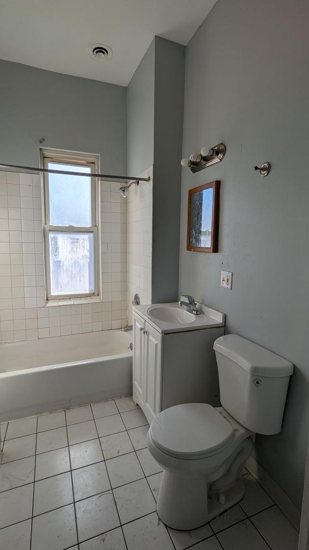 full bathroom featuring toilet, vanity, tile patterned flooring, and tiled shower / bath combo