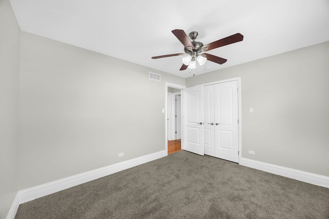 unfurnished bedroom featuring ceiling fan, dark carpet, and a closet