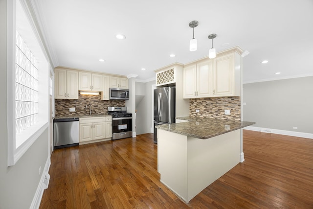 kitchen featuring kitchen peninsula, appliances with stainless steel finishes, dark stone counters, crown molding, and hanging light fixtures