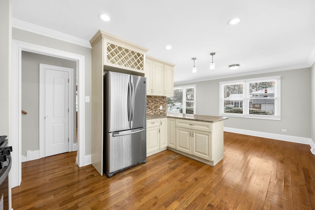 kitchen featuring cream cabinetry, stainless steel fridge, kitchen peninsula, and ornamental molding