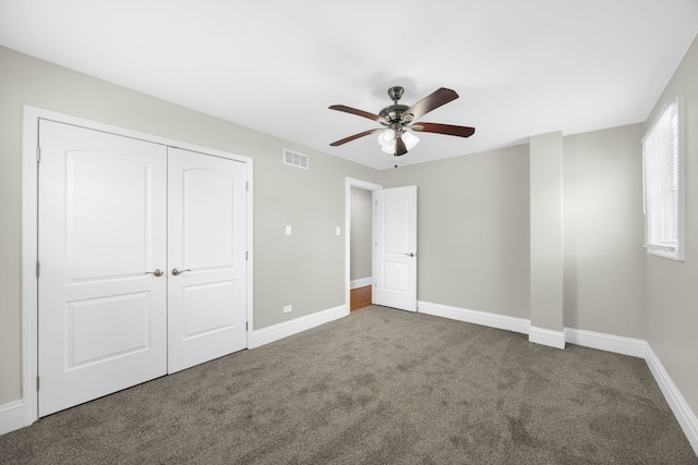 unfurnished bedroom with ceiling fan, dark carpet, and a closet