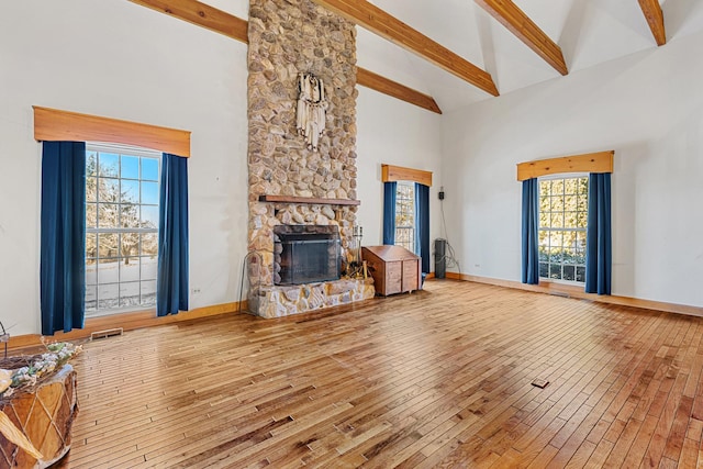 unfurnished living room with hardwood / wood-style flooring, a fireplace, high vaulted ceiling, and beamed ceiling