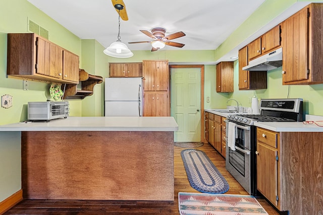 kitchen with kitchen peninsula, range with two ovens, dark wood-type flooring, white refrigerator, and pendant lighting