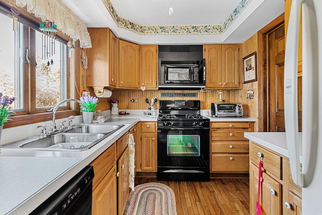 kitchen featuring black appliances, a raised ceiling, sink, and light hardwood / wood-style flooring