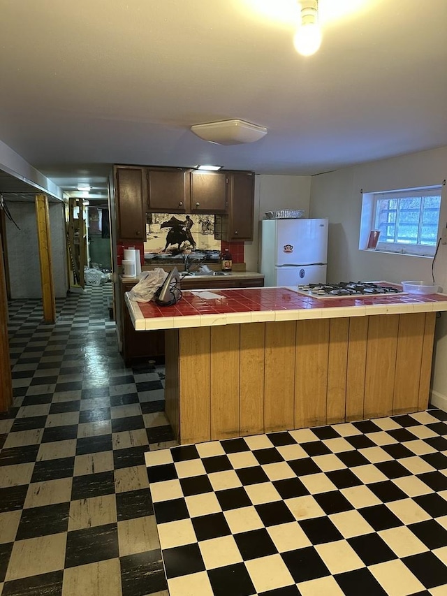 kitchen featuring white appliances, kitchen peninsula, and tile counters