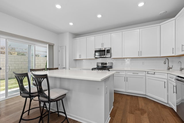 kitchen featuring white cabinets, a kitchen island, dark hardwood / wood-style flooring, and appliances with stainless steel finishes