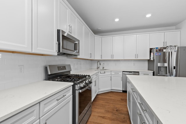 kitchen with light stone countertops, stainless steel appliances, white cabinetry, and sink