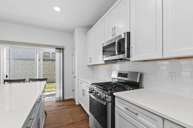 kitchen with light stone countertops, tasteful backsplash, dark hardwood / wood-style flooring, white cabinetry, and stainless steel appliances