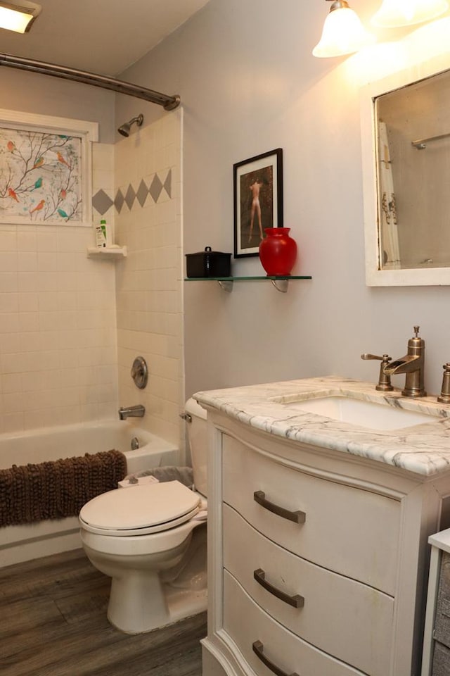 full bathroom featuring vanity, wood-type flooring, tiled shower / bath combo, and toilet