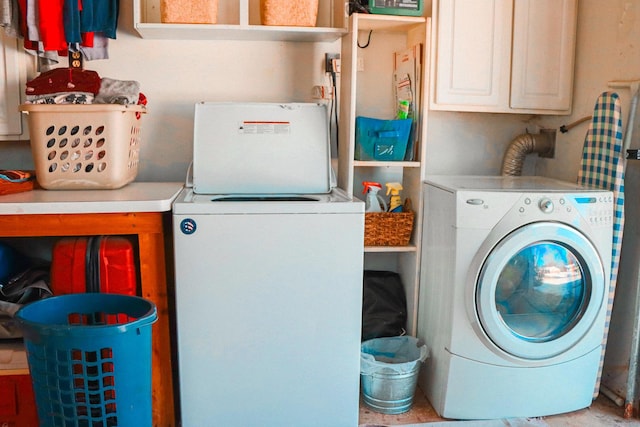 clothes washing area featuring cabinets and washer and dryer