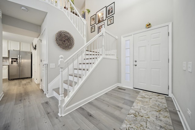 entrance foyer featuring light wood-type flooring and a towering ceiling