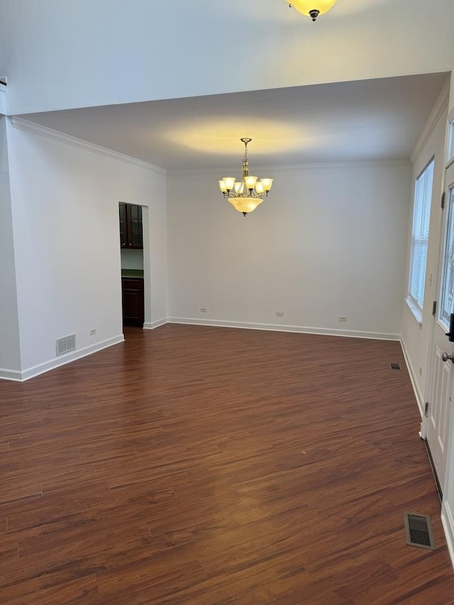 unfurnished room featuring dark wood-type flooring, ornamental molding, and a notable chandelier