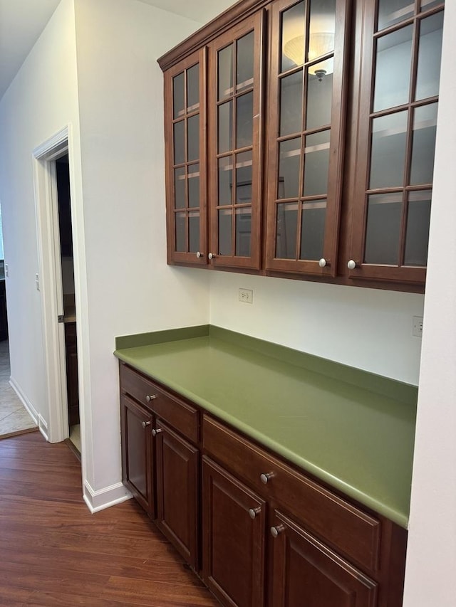 bar with dark hardwood / wood-style flooring and dark brown cabinets