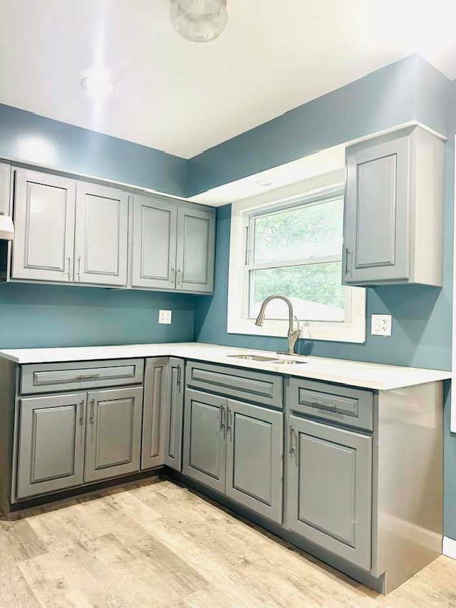 kitchen with sink, gray cabinetry, and light hardwood / wood-style floors