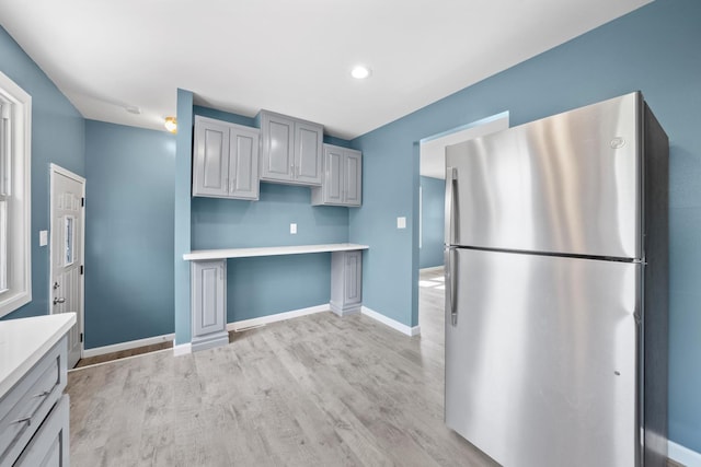 kitchen featuring light hardwood / wood-style flooring, gray cabinets, and stainless steel refrigerator