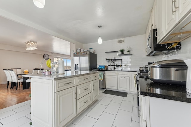 kitchen with stainless steel refrigerator with ice dispenser, backsplash, decorative light fixtures, white cabinets, and a kitchen island