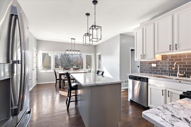 kitchen with decorative light fixtures, sink, white cabinets, a center island, and stainless steel appliances