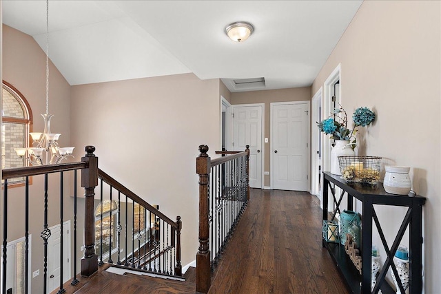 hallway with vaulted ceiling, dark hardwood / wood-style floors, and a notable chandelier