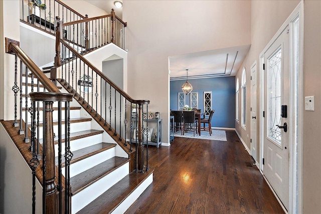 foyer entrance featuring a towering ceiling and dark hardwood / wood-style floors