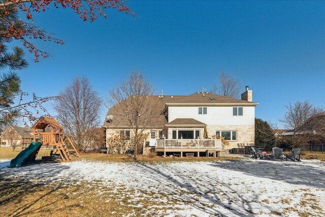 snow covered back of property with a playground