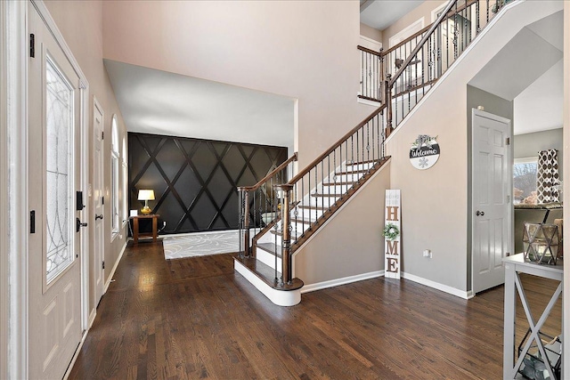 entryway with a towering ceiling and dark hardwood / wood-style floors