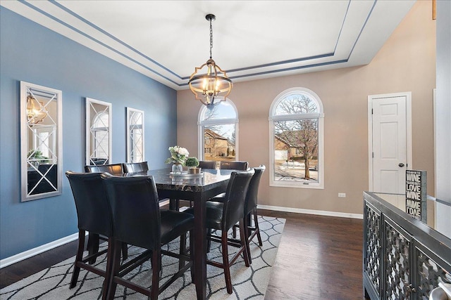 dining space with an inviting chandelier, dark hardwood / wood-style floors, and a raised ceiling