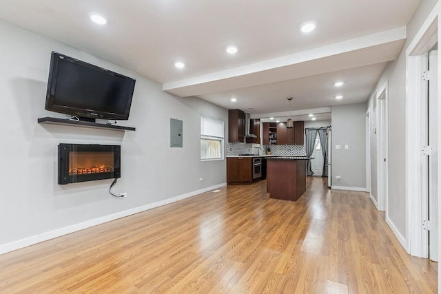 kitchen featuring light wood-type flooring, tasteful backsplash, stainless steel oven, decorative light fixtures, and a center island