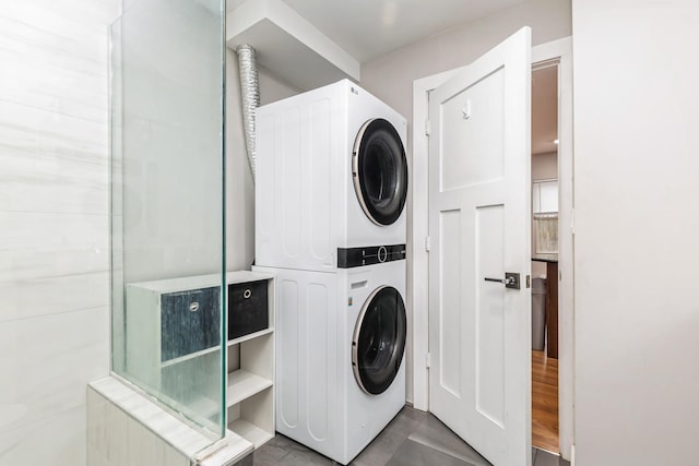 laundry room featuring stacked washing maching and dryer and tile patterned floors