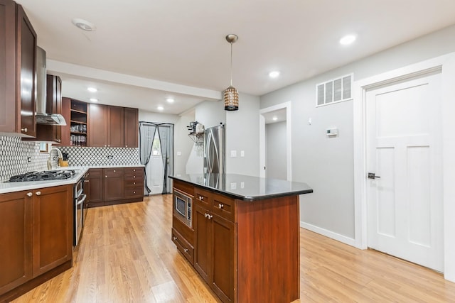 kitchen featuring stainless steel appliances, light hardwood / wood-style flooring, pendant lighting, decorative backsplash, and a kitchen island