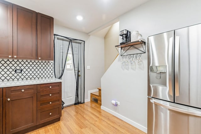 kitchen with stainless steel fridge, backsplash, and light hardwood / wood-style floors