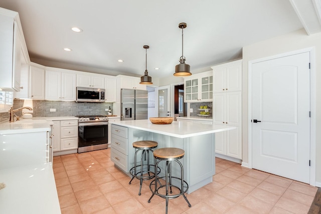 kitchen with appliances with stainless steel finishes, a kitchen island, pendant lighting, white cabinets, and sink