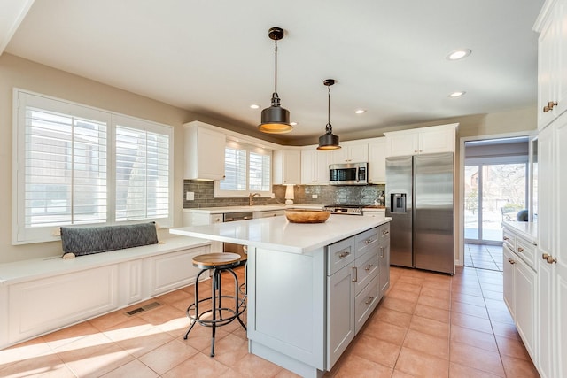 kitchen featuring appliances with stainless steel finishes, white cabinets, and a center island