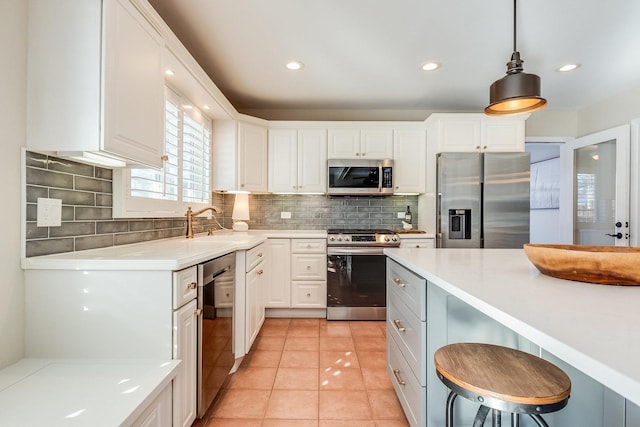 kitchen with decorative light fixtures, decorative backsplash, light tile patterned floors, appliances with stainless steel finishes, and white cabinets