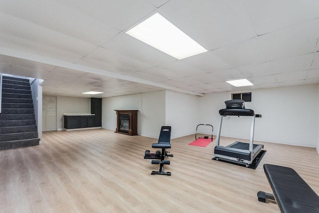 workout room with a paneled ceiling and light hardwood / wood-style flooring