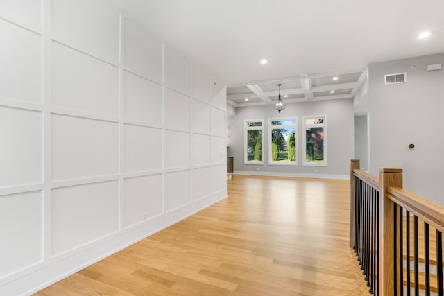 corridor with light wood-type flooring, coffered ceiling, and beamed ceiling