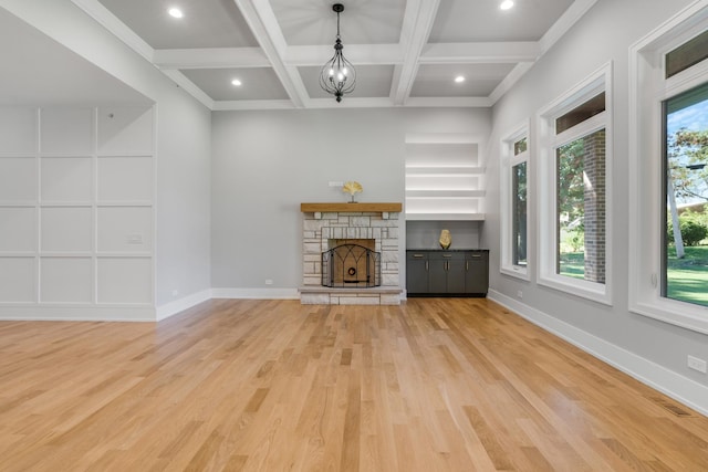 unfurnished living room featuring hardwood / wood-style flooring, coffered ceiling, beamed ceiling, and a fireplace