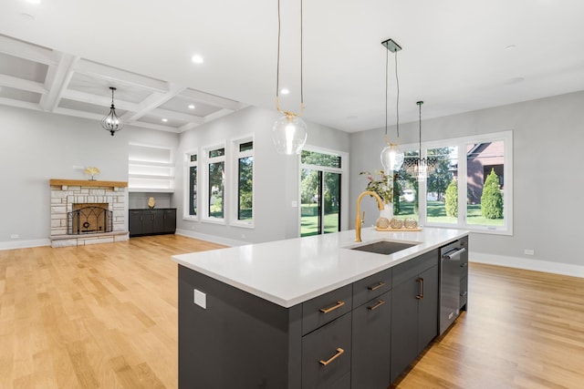 kitchen featuring stainless steel dishwasher, beam ceiling, a kitchen island with sink, coffered ceiling, and sink