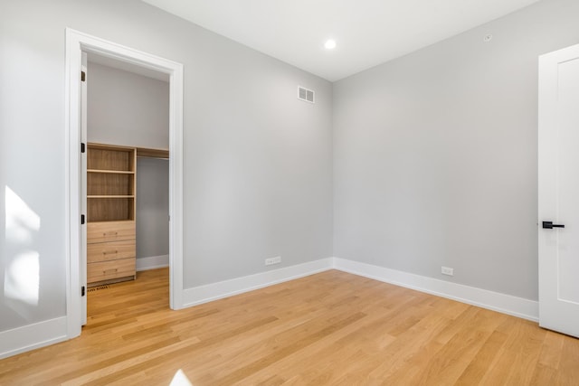 unfurnished bedroom featuring a closet, light hardwood / wood-style flooring, and a spacious closet