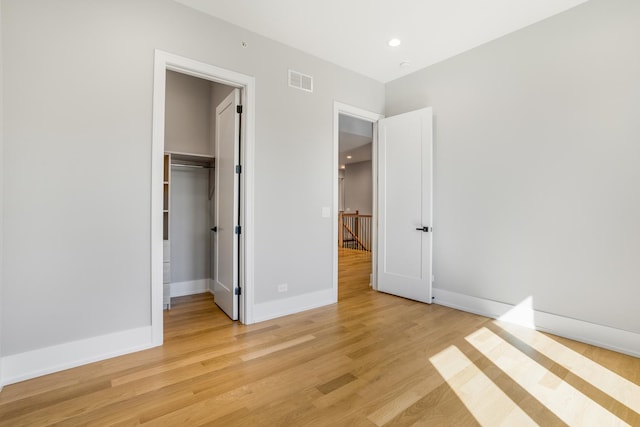 unfurnished bedroom with light hardwood / wood-style floors, a spacious closet, and a closet