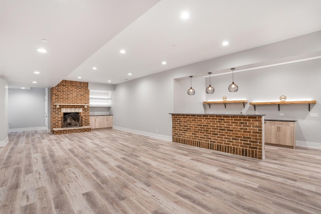 unfurnished living room with light hardwood / wood-style floors, a fireplace, and built in shelves