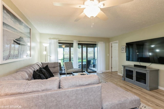 living room with a textured ceiling, light hardwood / wood-style flooring, and ceiling fan