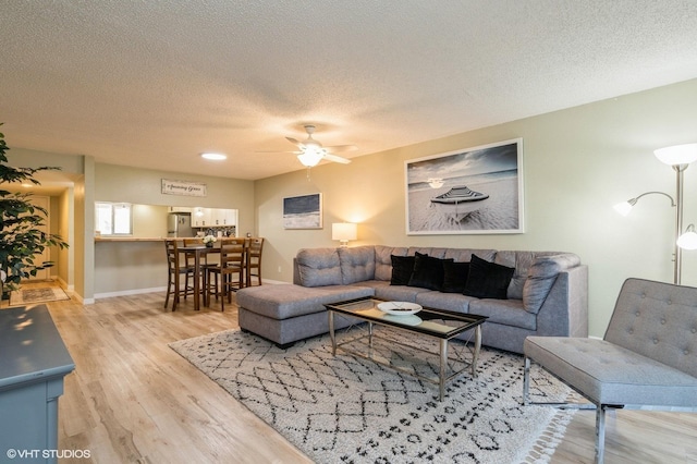 living room featuring a textured ceiling, light hardwood / wood-style floors, and ceiling fan